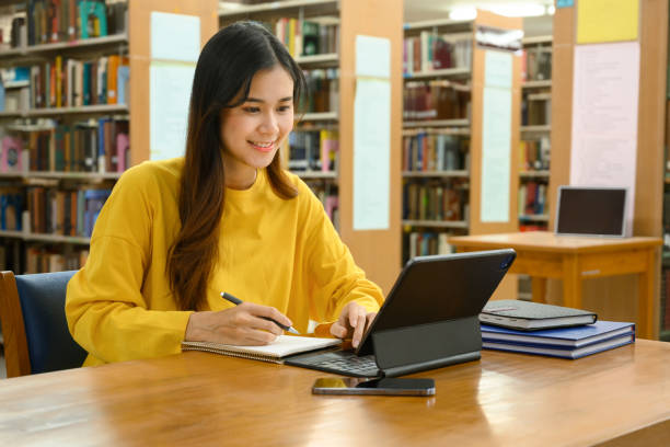 Student girl with tablet in library attending PTE online class